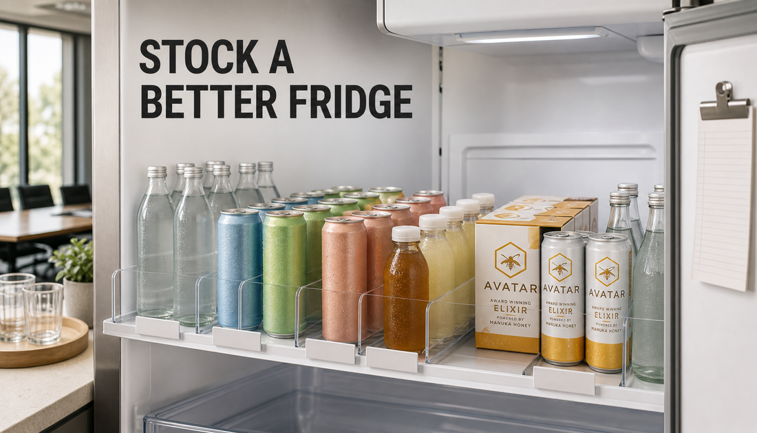 Open office fridge with a neatly organized shared drinks shelf, including water, sparkling drinks, low and no caffeine options, mixers, and Avatar Manuka Honey Elixir as a clean c...
