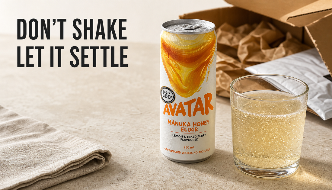 Avatar Elixir can set upright beside a calm sparkling honey drink pour, with delivery packaging behind it and headline text reading DON’T SHAKE LET IT SETTLE.